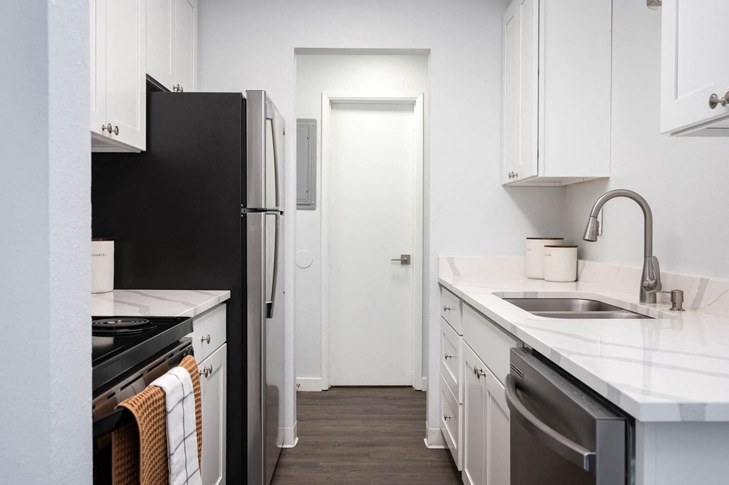 a kitchen with white cabinets and a black refrigerator